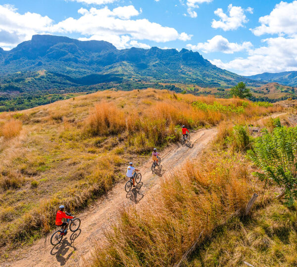 Cyclist riding an electric bike on a dirt road through Fiji's green Sabeto Valley below the Sleeping Giant range